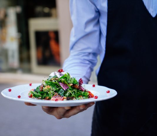 Se buscan camareros en Segovia Un camarero sirve un plato de comida en una foto de archivo.
