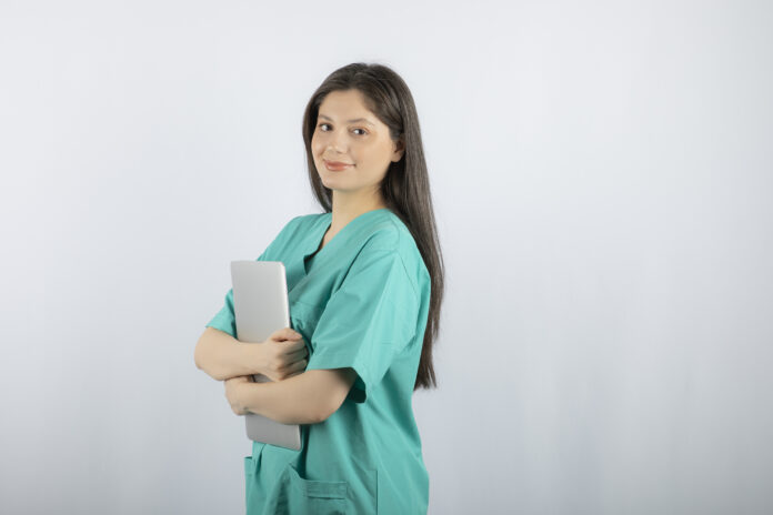 Portrait of young nurse holding laptop on white background Plazas enfermería